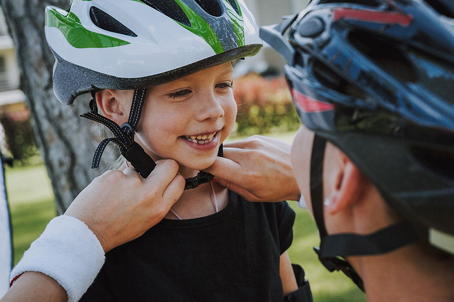 Parent putting a bike helmet on a child