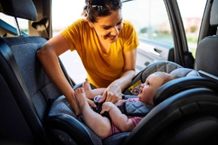 image-5 Infant being buckled in rear facing car seat by mom